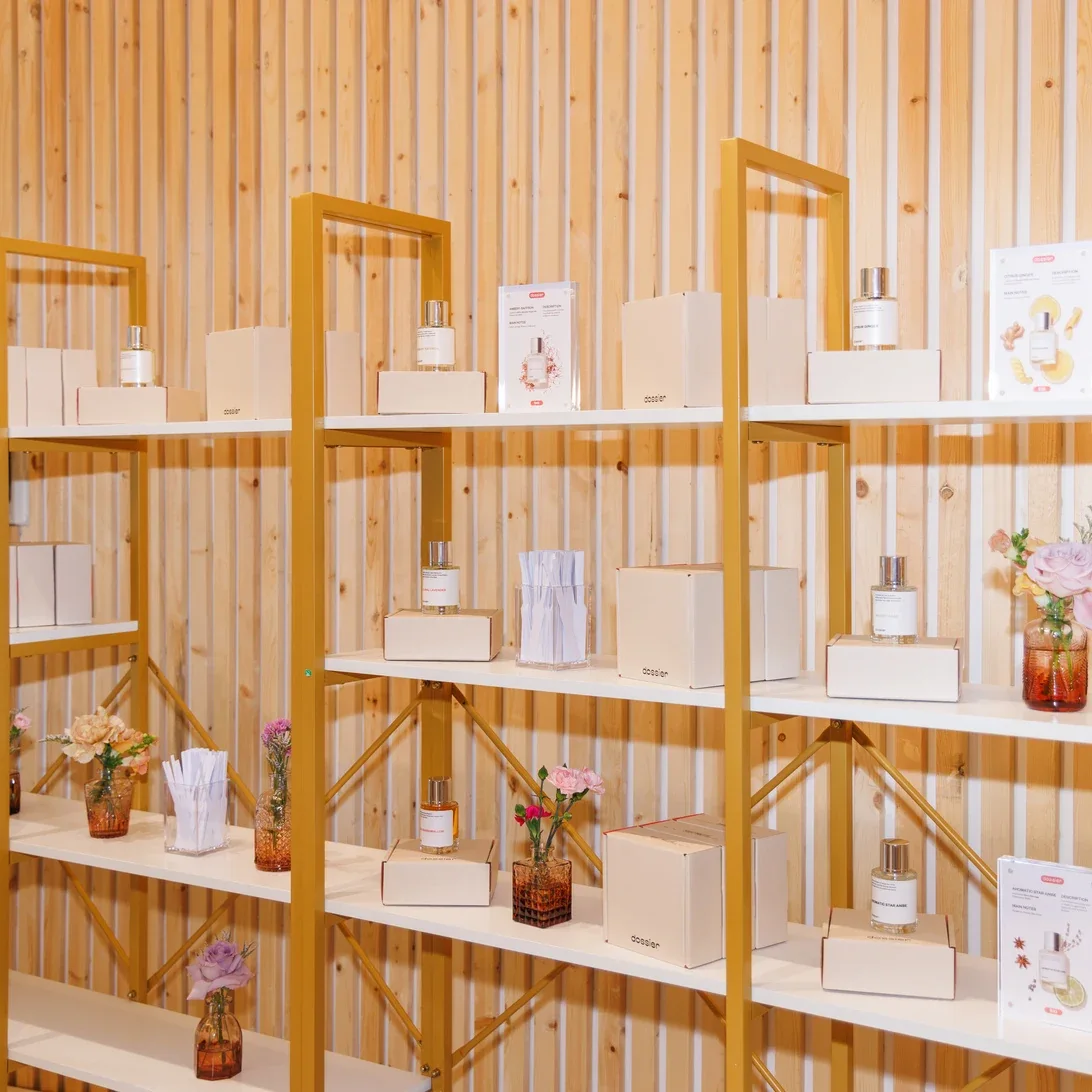 Dossier fragrance displays with gold-toned shelving, timber slats and small floral arrangements